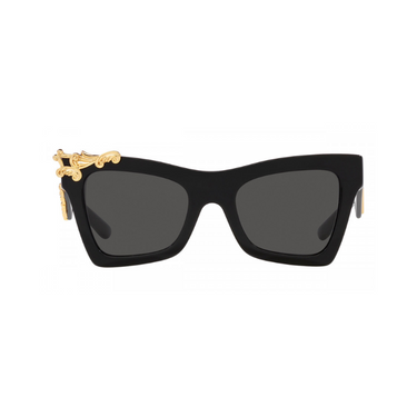 "Gafas Dolce & Gabbana negras con lentes oscuras. Las gafas tienen un diseño distintivo con adornos dorados. Hay un elemento decorativo dorado en la esquina superior izquierda del marco y un logotipo dorado 'DG' en la patilla del brazo derecho. El marco tiene una forma angular y audaz, lo que le da un aspecto estilizado y lujoso."