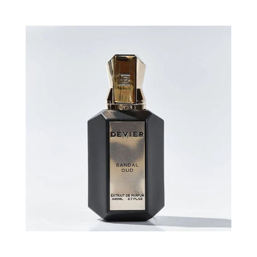 "perfume devier sandal oud color ngro y dorado en fondo azul"